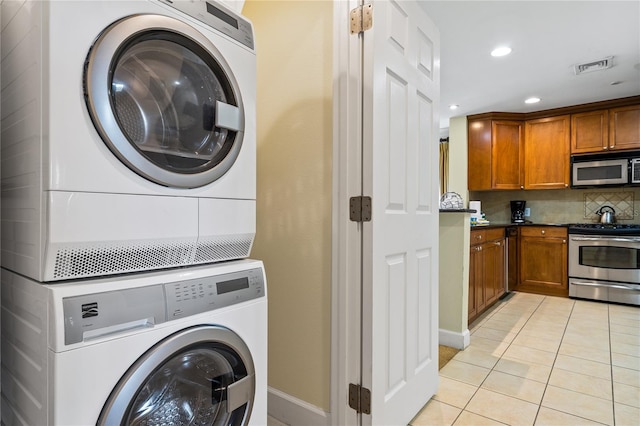 clothes washing area with light tile patterned floors and stacked washer / dryer