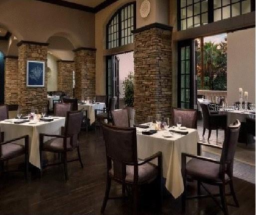 dining space with ornamental molding, dark wood-type flooring, a high ceiling, and decorative columns