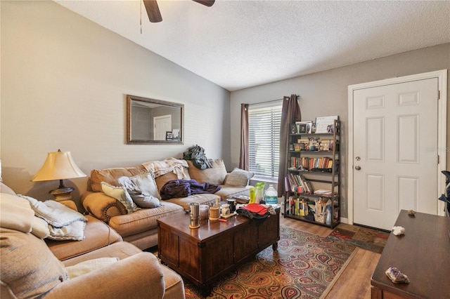 living room featuring ceiling fan, dark hardwood / wood-style flooring, lofted ceiling, and a textured ceiling