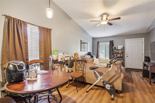 dining room with hardwood / wood-style floors, ceiling fan, lofted ceiling, and a textured ceiling