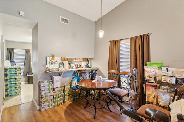 dining area with light wood-type flooring and vaulted ceiling