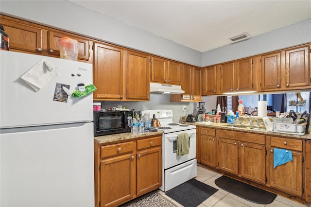 kitchen featuring light stone counters, sink, light tile patterned floors, and white appliances