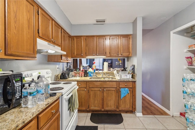 kitchen with white range with electric cooktop, light tile patterned flooring, light stone countertops, and sink