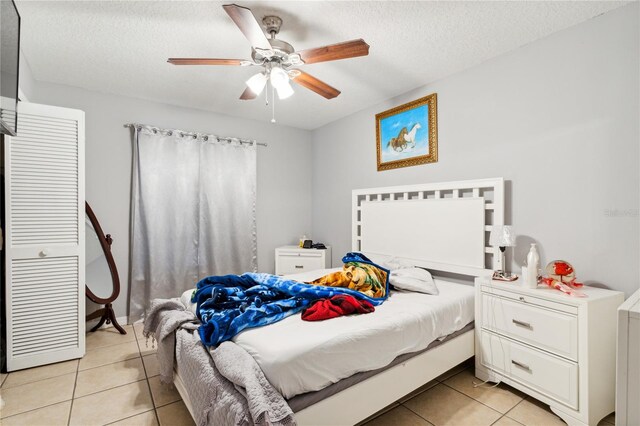 tiled bedroom featuring ceiling fan and a textured ceiling