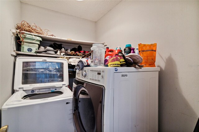 washroom with washing machine and clothes dryer and a textured ceiling