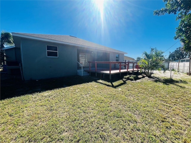 back of property featuring a deck and a lawn