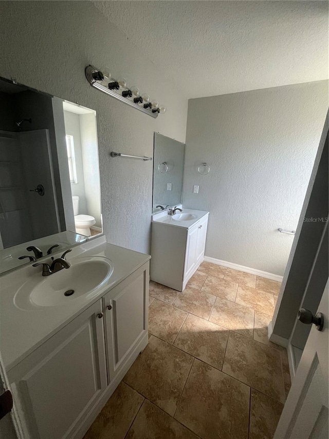 bathroom with tile patterned floors, vanity, a textured ceiling, and toilet