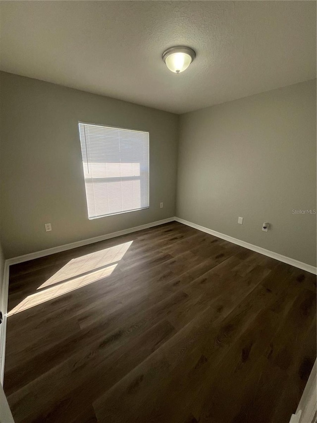 empty room with a textured ceiling and dark hardwood / wood-style floors