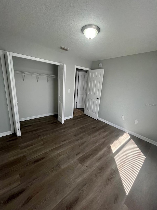 6336 Florida Cir, Apollo Beach, FL 33572 - unfurnished bedroom with dark wood finished floors, a closet, baseboards, and a textured ceiling