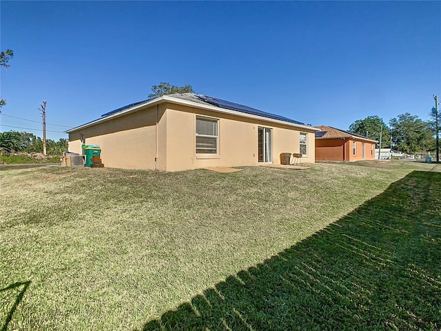 back of property featuring a lawn, central AC, and solar panels