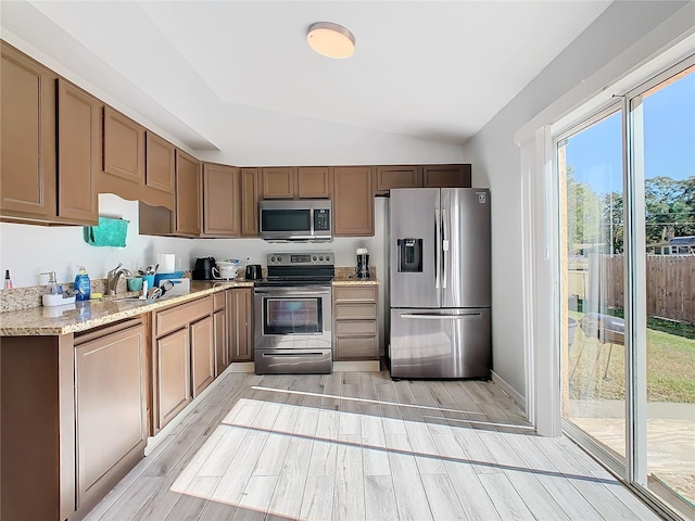 kitchen with plenty of natural light, stainless steel appliances, lofted ceiling, and light hardwood / wood-style floors