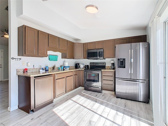 kitchen with sink, light wood-type flooring, lofted ceiling, and appliances with stainless steel finishes