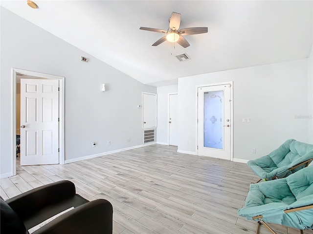 living room with ceiling fan, vaulted ceiling, and light wood-type flooring