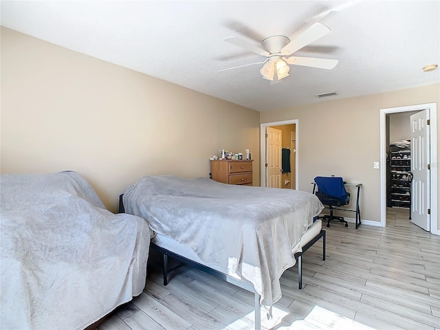 bedroom featuring a spacious closet, ceiling fan, and light wood-type flooring