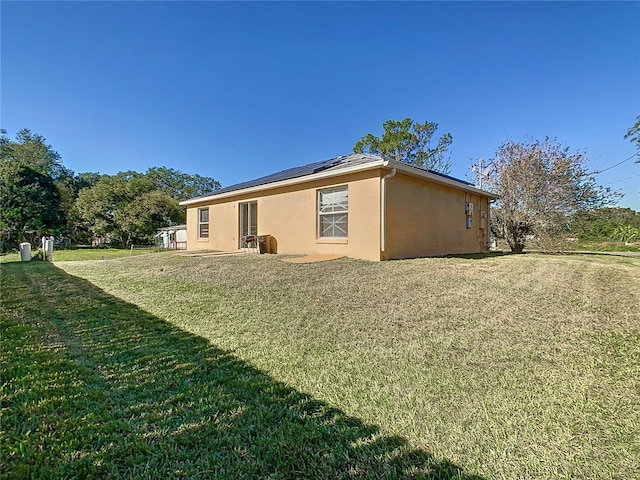 back of property featuring a lawn and solar panels