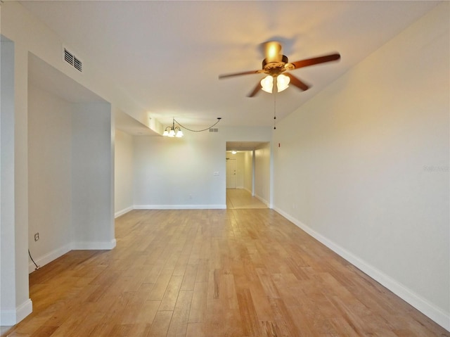 empty room featuring light hardwood / wood-style flooring and ceiling fan with notable chandelier