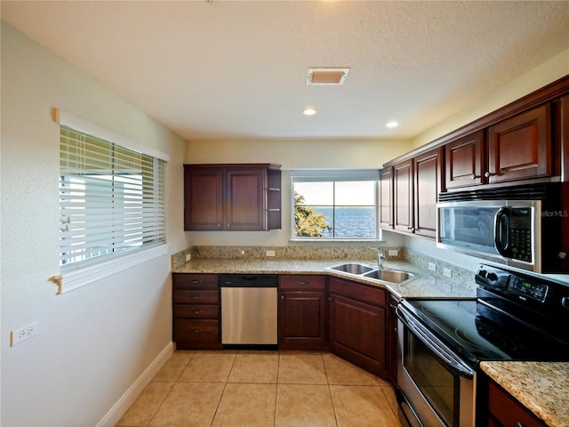 kitchen featuring light stone countertops, sink, light tile patterned floors, and appliances with stainless steel finishes