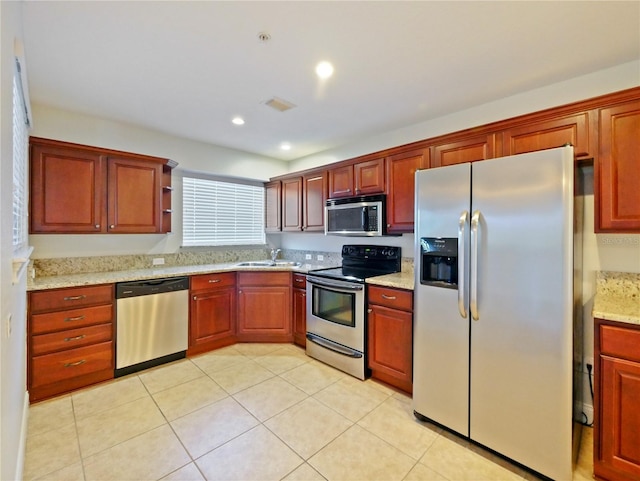 kitchen with light stone countertops, sink, light tile patterned floors, and stainless steel appliances