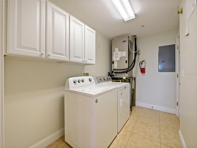 laundry room with cabinets, washing machine and dryer, electric panel, a textured ceiling, and light tile patterned floors