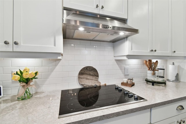 kitchen featuring white cabinets, black electric stovetop, and decorative backsplash