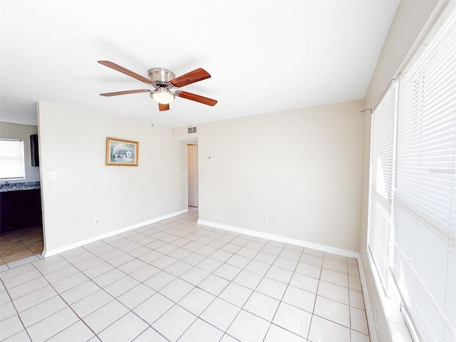 tiled empty room with ceiling fan and a healthy amount of sunlight