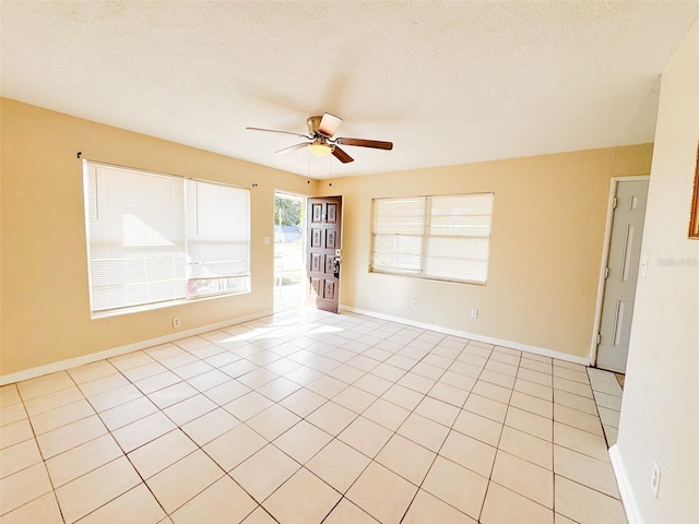 spare room with ceiling fan, light tile patterned flooring, and a textured ceiling