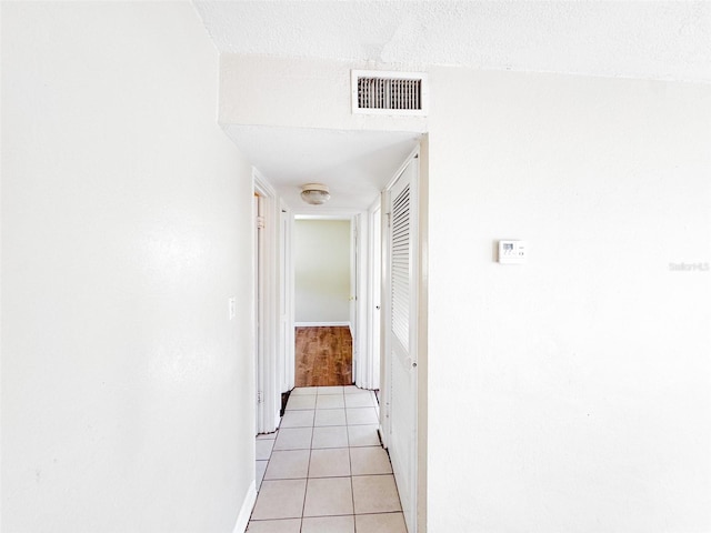 corridor with light tile patterned flooring and a textured ceiling