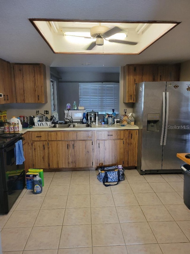 kitchen with light tile patterned floors, electric range, brown cabinetry, stainless steel fridge with ice dispenser, and light countertops