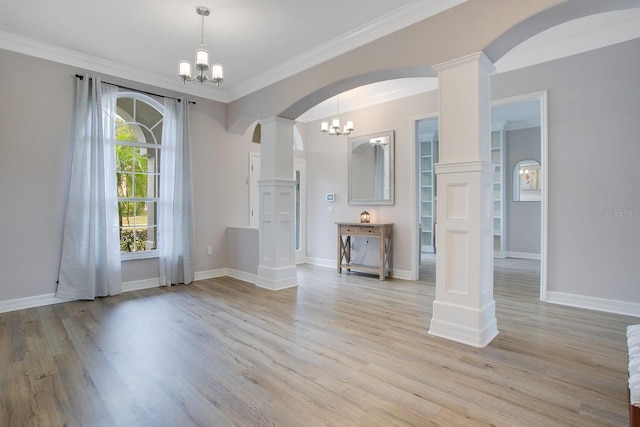 interior space with light hardwood / wood-style floors, an inviting chandelier, ornamental molding, and decorative columns