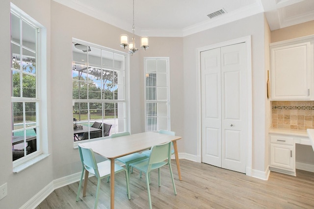 dining area featuring an inviting chandelier, light hardwood / wood-style flooring, and ornamental molding