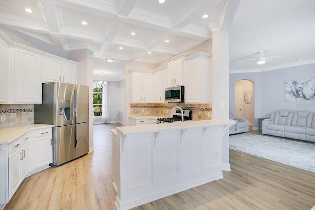 kitchen with white cabinetry, light hardwood / wood-style flooring, backsplash, kitchen peninsula, and appliances with stainless steel finishes