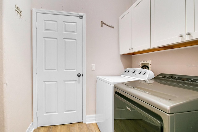 clothes washing area featuring cabinets, washing machine and dryer, and light hardwood / wood-style flooring