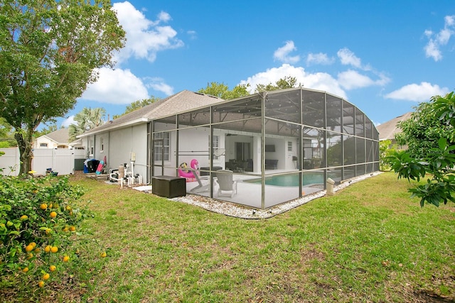 back of property with a fenced in pool, a lanai, and a lawn