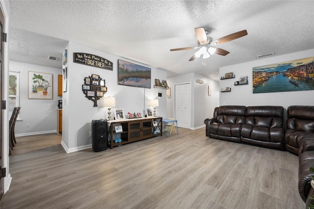 living room featuring a textured ceiling, ceiling fan, and light hardwood / wood-style flooring