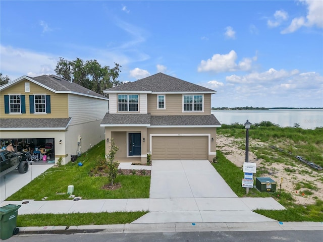 view of front facade with a front yard, a garage, and a water view