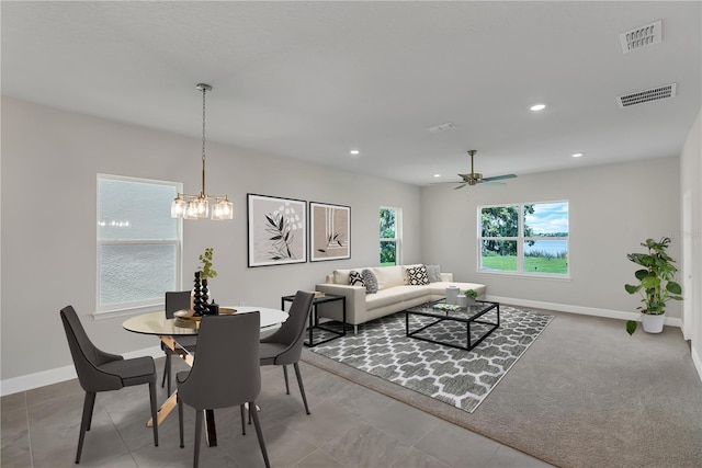 carpeted dining space featuring ceiling fan with notable chandelier