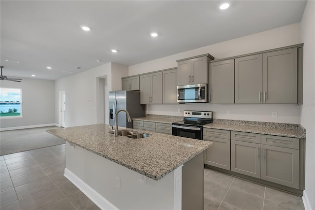 kitchen with light stone countertops, appliances with stainless steel finishes, gray cabinetry, ceiling fan, and sink