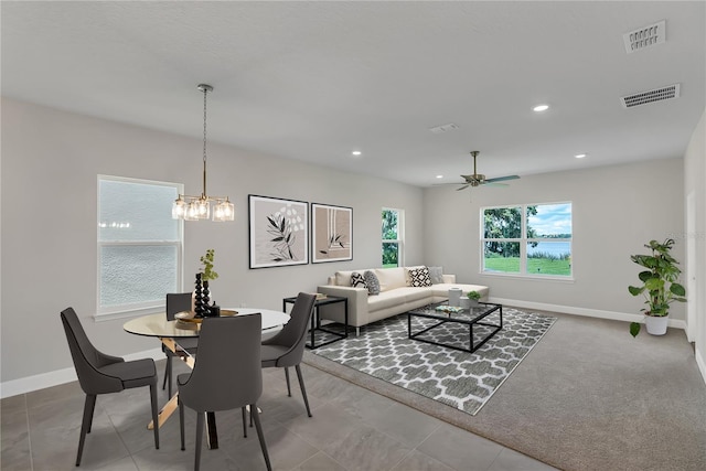 dining space with carpet flooring and ceiling fan with notable chandelier