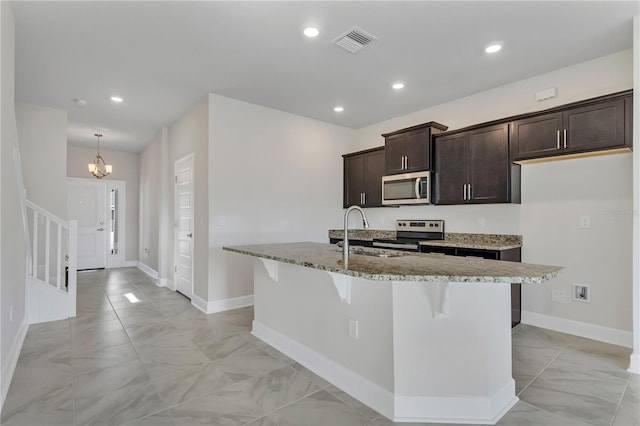 kitchen with appliances with stainless steel finishes, dark brown cabinetry, an island with sink, and sink