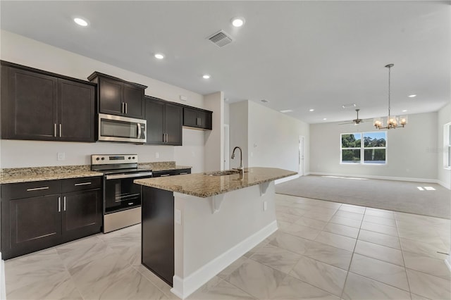 kitchen with sink, pendant lighting, a kitchen island with sink, ceiling fan with notable chandelier, and appliances with stainless steel finishes