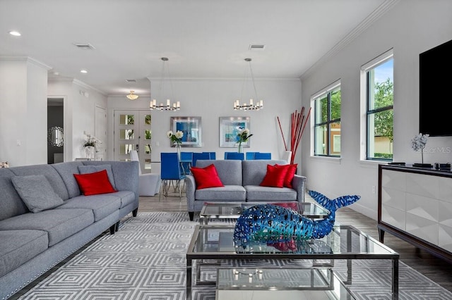 living room featuring french doors, light wood-type flooring, an inviting chandelier, and ornamental molding