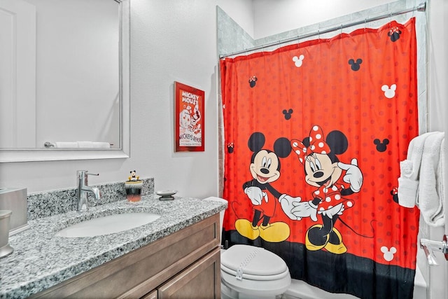 bathroom featuring walk in shower, vanity, and toilet