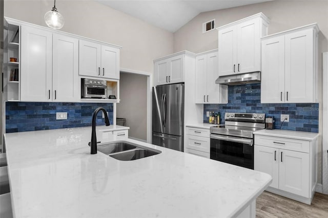 kitchen with white cabinets, decorative backsplash, stainless steel appliances, and hanging light fixtures