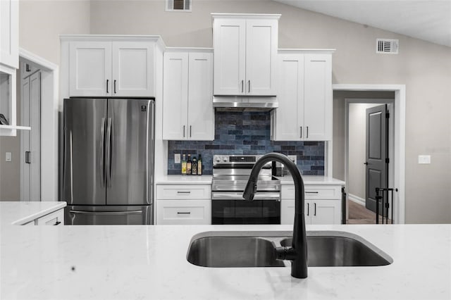 kitchen featuring white cabinets, stainless steel appliances, and vaulted ceiling