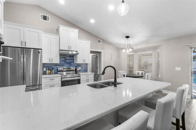 kitchen with pendant lighting, white cabinets, sink, vaulted ceiling, and stainless steel appliances