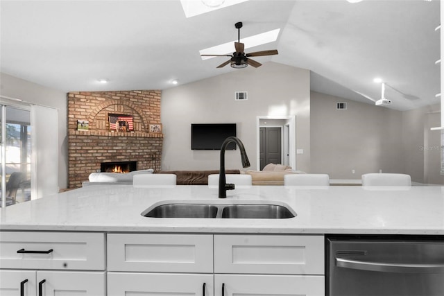 kitchen with white cabinetry, dishwasher, lofted ceiling with skylight, and sink