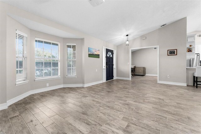 unfurnished living room with lofted ceiling and light wood-type flooring