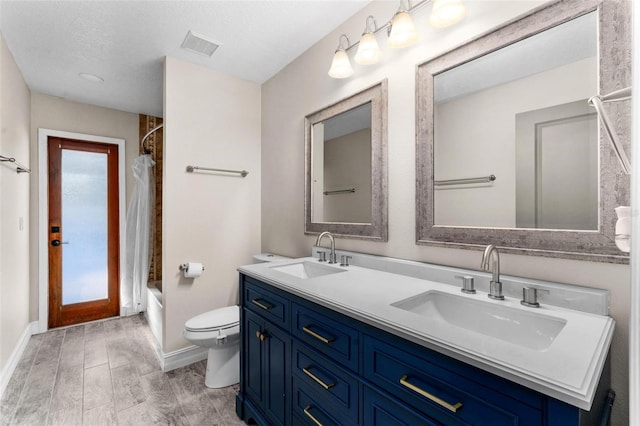 full bathroom featuring vanity, a textured ceiling, wood-type flooring, shower / bathtub combination with curtain, and toilet