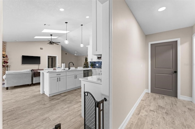 kitchen featuring white cabinets, light hardwood / wood-style floors, stainless steel dishwasher, and kitchen peninsula