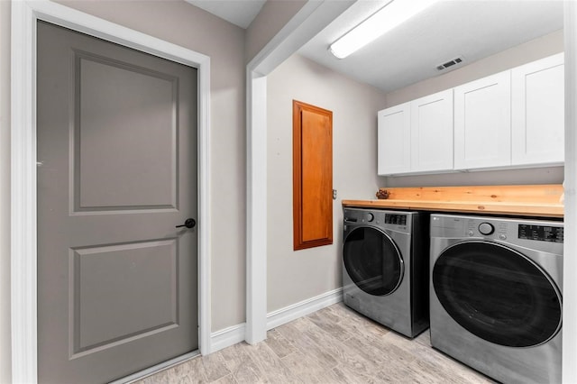 laundry area featuring cabinets, light wood-type flooring, and washing machine and clothes dryer